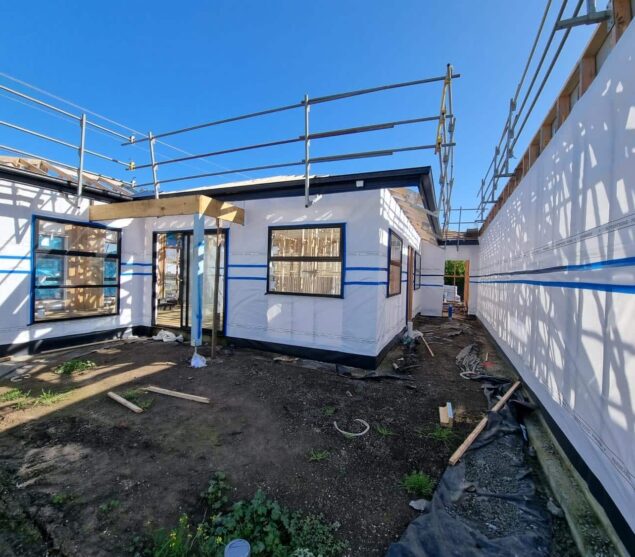 Exposed wall framing and scaffolding before commercial insulation installation